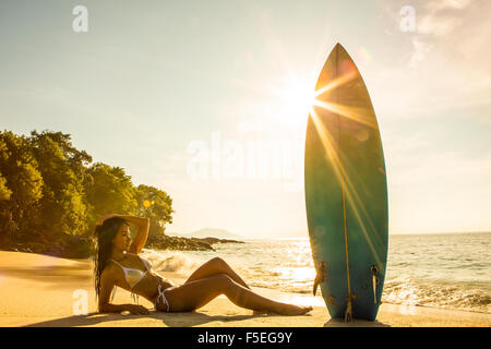 Woman lying on the beach with a surfboard, Bali, Indonesia Stock Photo