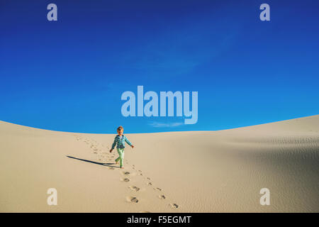 Boy running down a sand dune Stock Photo