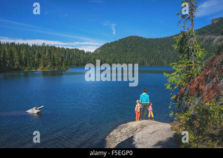 Man with two children standing on a rock by lake Stock Photo