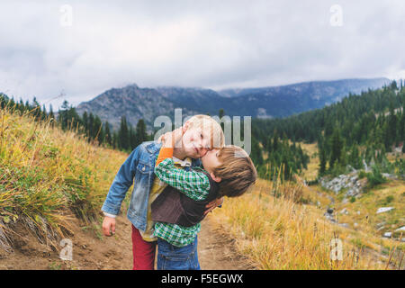Two brothers hugging and kissing on mountain path