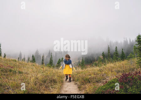 Girl walking along  mountain path in the fog Stock Photo