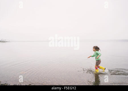 Girl running in a lake wearing wellington boots Stock Photo