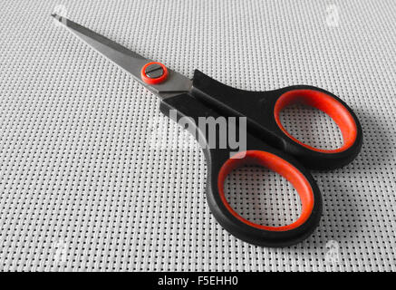 Red and black scissors on white mat Stock Photo