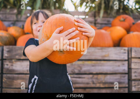 Girl holding large pumpkin at pumpkin farm Stock Photo