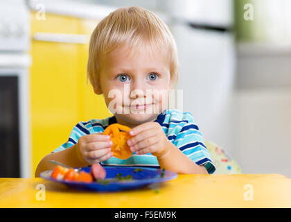 Cute little boy eats his lunch sitting at a table in the kitchen Stock Photo