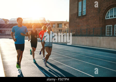 Professional runners running on a race track. Multiracial athletes practicing on race track in stadium on a bright sunny day. Stock Photo