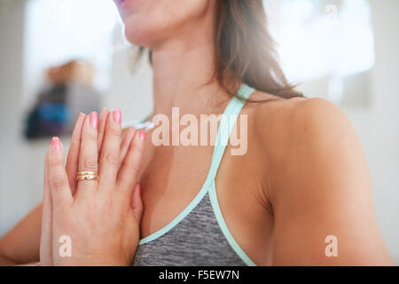 Close up image of woman practicing yoga with her hands joined. Focus on hands. Fitness female meditating in gym. Stock Photo