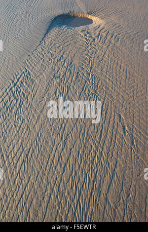 Water patterns on sand with shadows and morning light Stock Photo