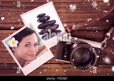 Composite image of beautiful brunette relaxing on massage table smiling at camera Stock Photo