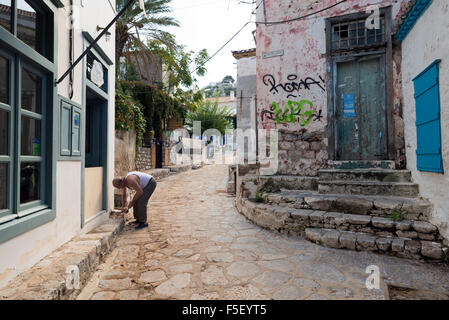 HYDRA, GREECE - OCTOBER 25, 2015: A man repairs the sidewalk of a street in Hydra, an island in Greece Stock Photo