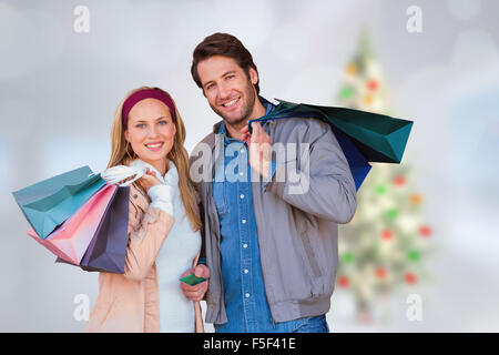 Composite image of smiling couple with shopping bags in front of window Stock Photo