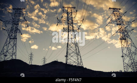 High voltage power lines and towers in silhouette against sunset sky and clouds Stock Photo