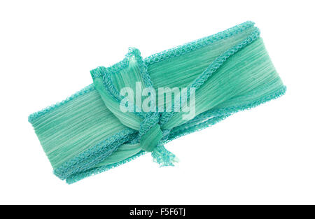 A small length of green ribbon cloth with a binding stitch tied isolated on a white background. Stock Photo