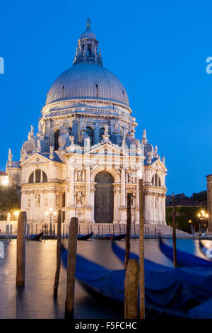 Santa Maria della Salute church basilica with gondolas in foreground from across Grand Canal at night twilight dusk Venice Venet Stock Photo