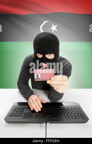 Hacker with ID card in hand and flag on background - Libya Stock Photo