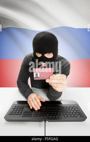 Hacker with ID card in hand and flag on background - Russia Stock Photo