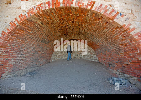 Man in huge interior of historic lime burning kiln with high arched red brick ceiling & walls at Wool Bay, Yorke Peninsula SA Stock Photo