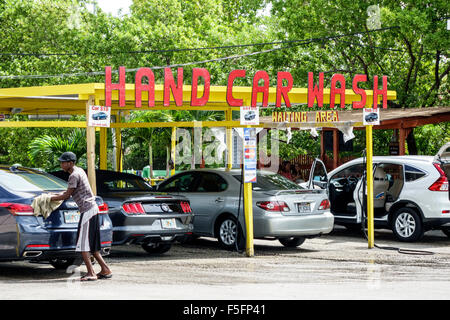 African American man, car wash worker is spraying cleaning foam to