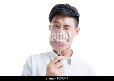 Young man holding a magnifying glass in front of his mouth Stock Photo