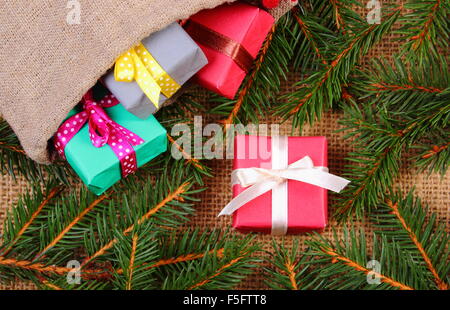 Wrapped colorful gifts for Christmas, birthday or other celebration in jute bag and spruce branches on jute canvas Stock Photo