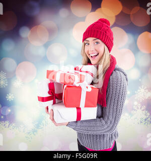 Composite image of festive blonde holding pile of gifts Stock Photo