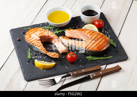 Grilled salmon, salad and condiments on wooden table Stock Photo