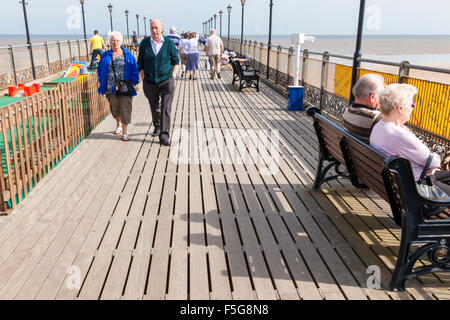 People at the seaside walking and sitting on Skegness pier, Skegness, Lincolnshire, England, UK Stock Photo