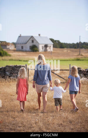 Sweden, Gotland, Faro, Mother with son (2-3) and daughters (8-9, 10-11) walking in farm yard Sweden, Gotland, Faro, Mother with son (2-3) and daughters (8-9, 10-11) walking in farm yard