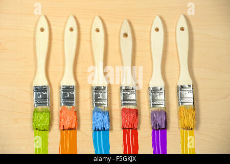 Six paintbrushes with paint of different colors over wood Stock Photo