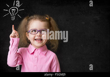 kid in glasses with idea lamp on school chalkboard Stock Photo