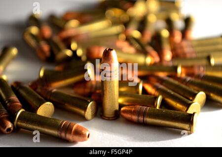 single standing bullet amongst other in a pile on white background Stock Photo