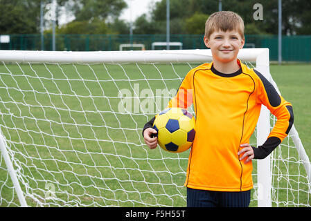 Portrait Of Goal Keeper Holding Ball On School Soccer Pitch Stock Photo