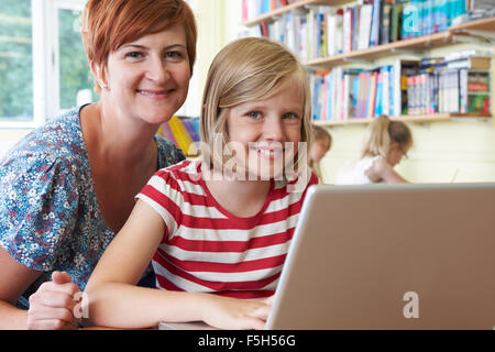 School Pupil With Teacher Using Laptop Computer In Classroom Stock Photo