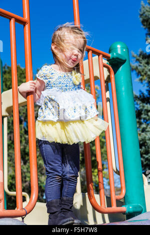 Four year old little girl playing outside on a jungle gym in a park Stock Photo