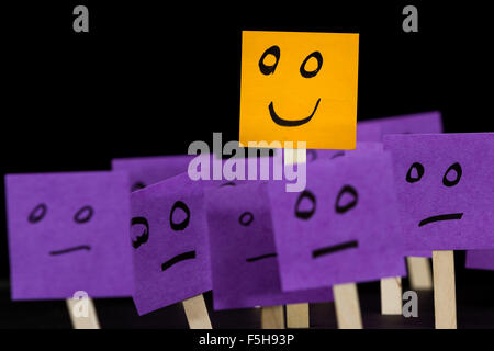 conceptual image using sticky notes with hand drawn faces on them isolated on a black background Stock Photo