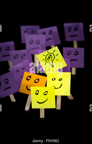 conceptual image using sticky notes with hand drawn faces on them isolated on a black background Stock Photo