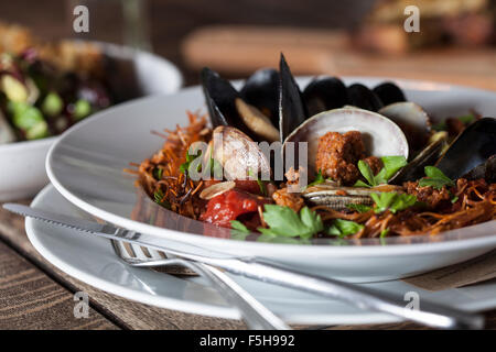 close-up of mussels, clams, pasta on a white plate with fork and knife Stock Photo