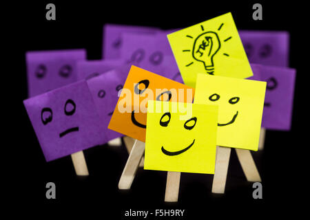 conceptual image using sticky notes with hand drawn faces on them isolated on a black background Stock Photo