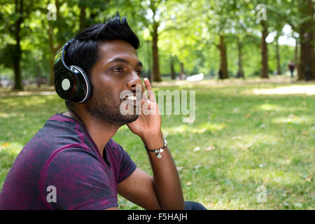 young man listening to music in the park Stock Photo