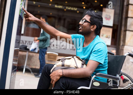 disabled man looking at a street map in his wheelchair. Stock Photo