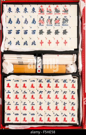 MahJong gambling game open box ivory set. Top down view of tiles arranged in order with various pieces arranged in the centre with dice. Stock Photo