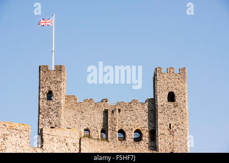 England, Rochester Castle. Top of typical Norman keep corner turrets. Flagpole on one with Union Jack flag flying above. Blue clear sky. Stock Photo
