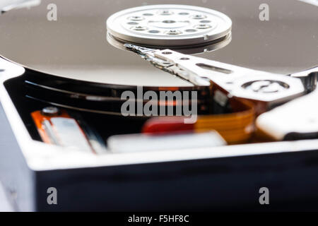 Interior of computer hard drive. Actuator arm with read and write heads over the platter and disk. Macro close up. Stock Photo