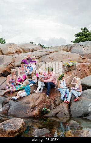 Sweden, Uppland, Roslagen, Big family having picnic on rocks at seaside Stock Photo