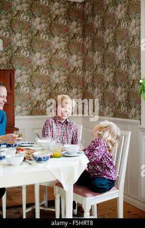 Sweden, Mother with two children (2-3, 10-11) eating breakfast