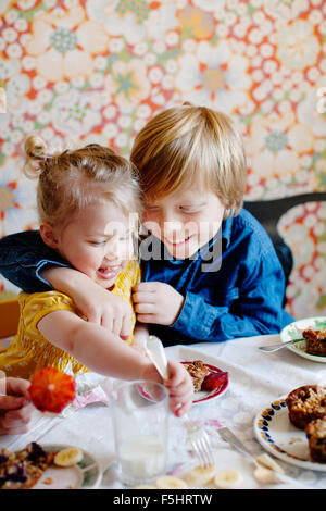Sweden, Boy (10-11) and girl (2-3) eating cake