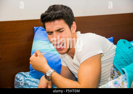 Close Up of Attractive Young Man Lying in Bed and Coughing, Disgusted by Cough Syrup, or Gagging - Sick Man Making Disgusted Fac Stock Photo