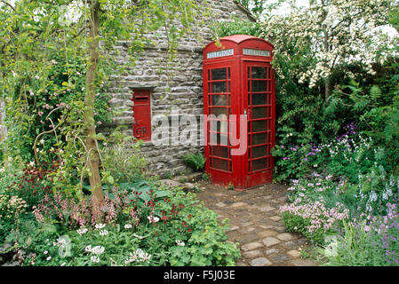 Vintage post box on stone wall in garden with a red vintage telephone box Stock Photo