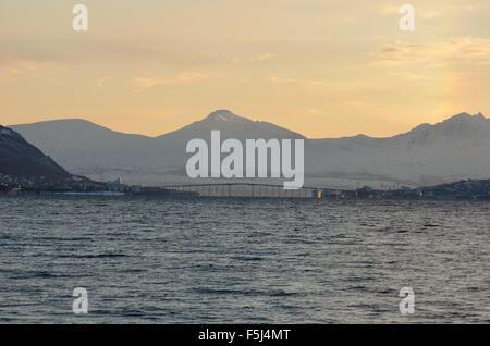 tromsoe city mainland and the connecting bridge over blue fjord water, mighty mountain and sky backdrop Stock Photo