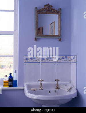 Small antique gilt mirror above washbasin in a blue bathroom Stock Photo